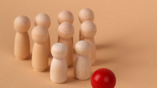 Wooden figures representing leadership and individuality on a neutral background.