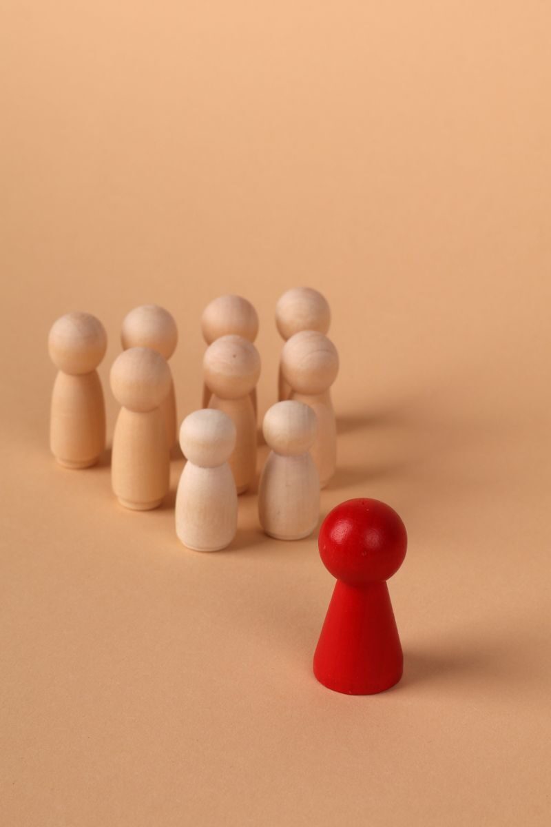 Wooden figures representing leadership and individuality on a neutral background.