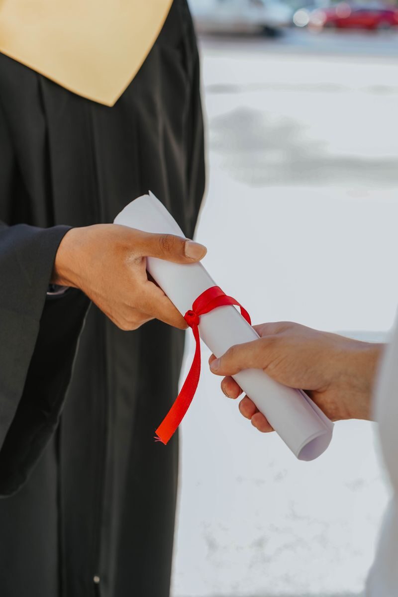 Hands exchanging a graduation diploma wrapped with red ribbon, symbolizing achievement.