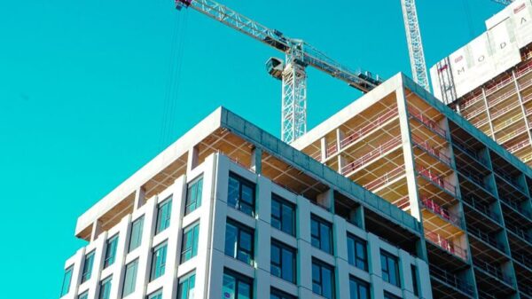 High-rise building under construction with cranes against a clear sky.