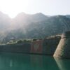 Explore the majestic Kotor fortress basking in sunlight, framed by mountains.