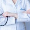 A close-up image of a doctor in a white coat with a stethoscope and arms crossed.