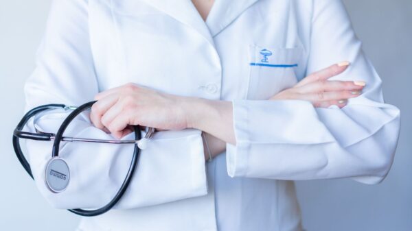 A close-up image of a doctor in a white coat with a stethoscope and arms crossed.