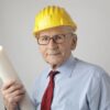 Senior engineer in safety gear holding blueprints, symbolizing experience and dedication in civil engineering.