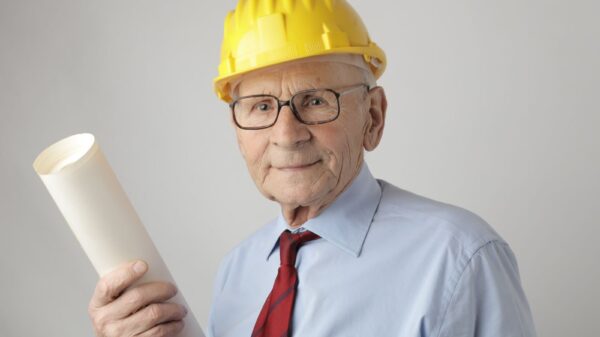 Senior engineer in safety gear holding blueprints, symbolizing experience and dedication in civil engineering.