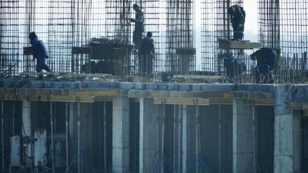 Construction workers at a high-rise building site with visible steel reinforcements.