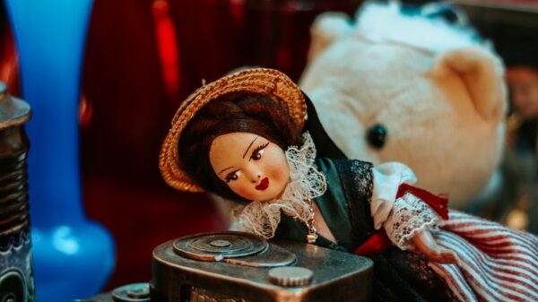 Charming vintage setup featuring a doll, toy camera, and decorative glassware, captured with warm tones.