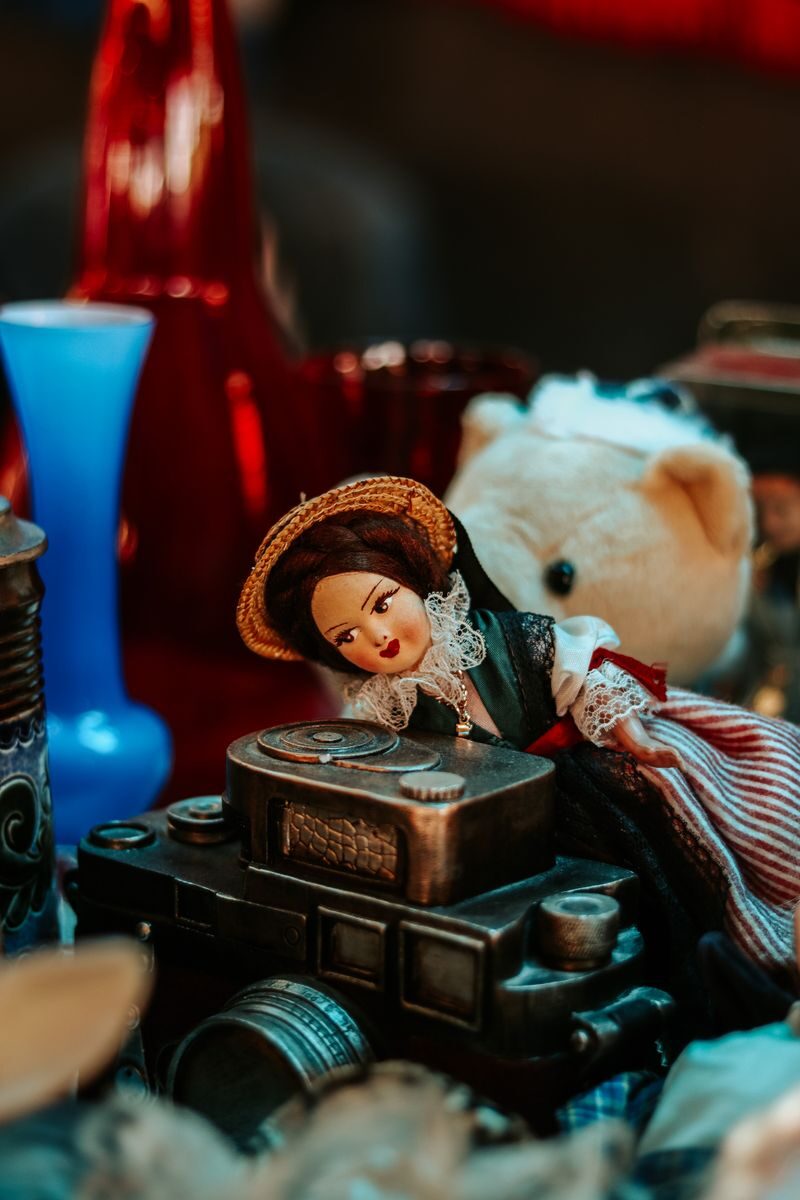 Charming vintage setup featuring a doll, toy camera, and decorative glassware, captured with warm tones.