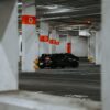 A stylish black sports car parked in a modern, empty urban parking garage.