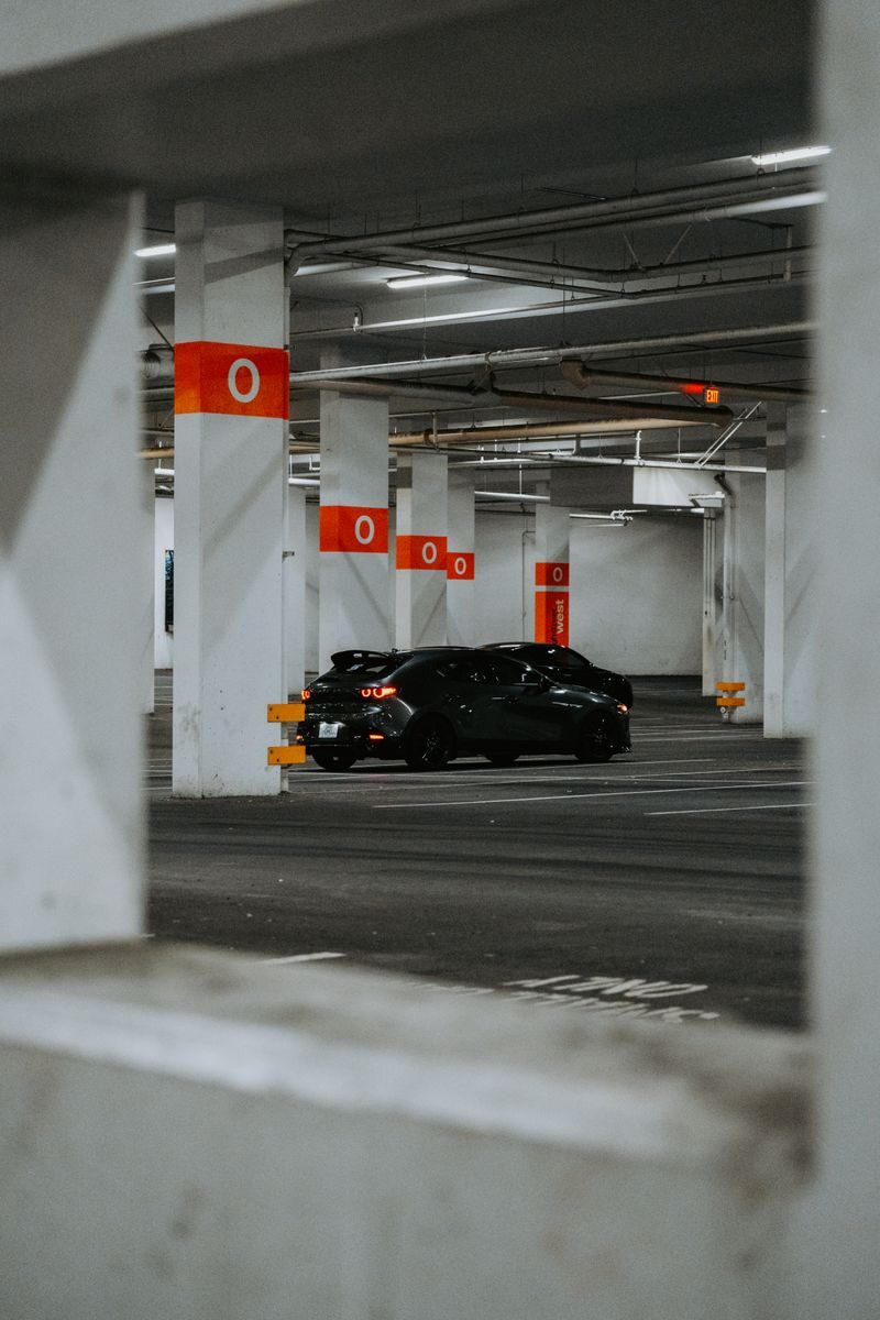 A stylish black sports car parked in a modern, empty urban parking garage.