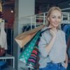 Smiling woman carrying shopping bags in a stylish clothing store.
