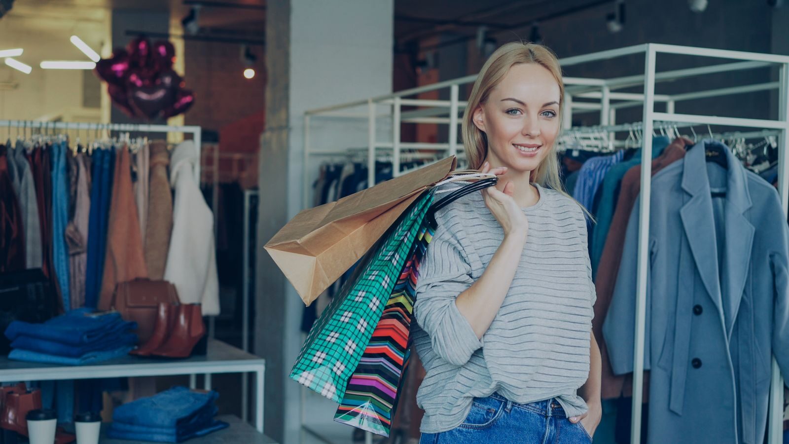 Smiling woman carrying shopping bags in a stylish clothing store.