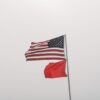 United States and warning flags on display against an overcast sky at Orange Beach, AL.