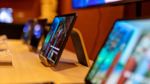 Close-up of modern tablets displayed on a wooden table in an electronics store.