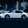 A dynamic shot of a white Porsche in motion on a street in San Diego, capturing speed and elegance.