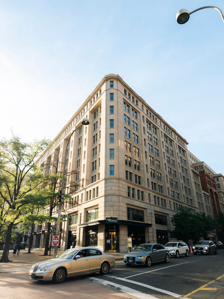 A classic corner building in Washington DC with cars, captured during a sunny day.