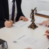 Lawyers reviewing and signing divorce decree documents in a formal office setting.