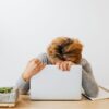 Woman showing fatigue resting head on laptop, workspace stress.