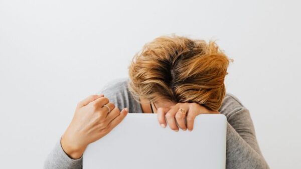Woman showing fatigue resting head on laptop, workspace stress.