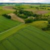 Aerial panorama showcasing vast green farmland fields in summer.