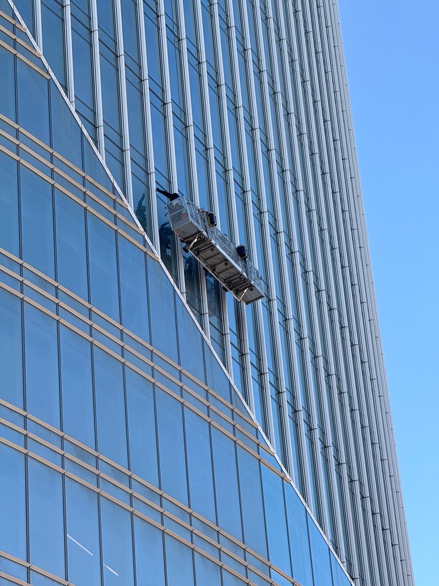 Professional window cleaners suspended on a high-rise building facade.