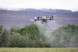 Aerial drone technology spraying crops in a rural farming landscape.
