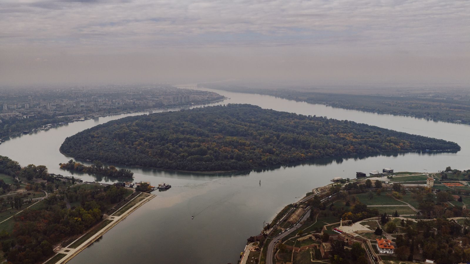 Stunning aerial shot of the river bend in Belgrade, Serbia, showcasing lush greenery and cityscape.
