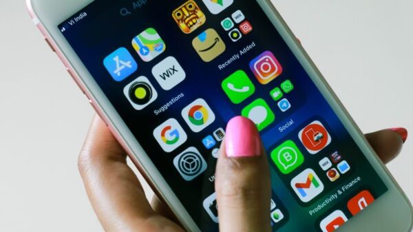 Close-up of a hand holding a smartphone displaying various apps on the screen.