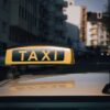 Close-up of a taxi sign on a car roof with an urban city background.