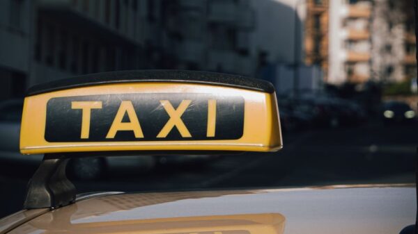 Close-up of a taxi sign on a car roof with an urban city background.