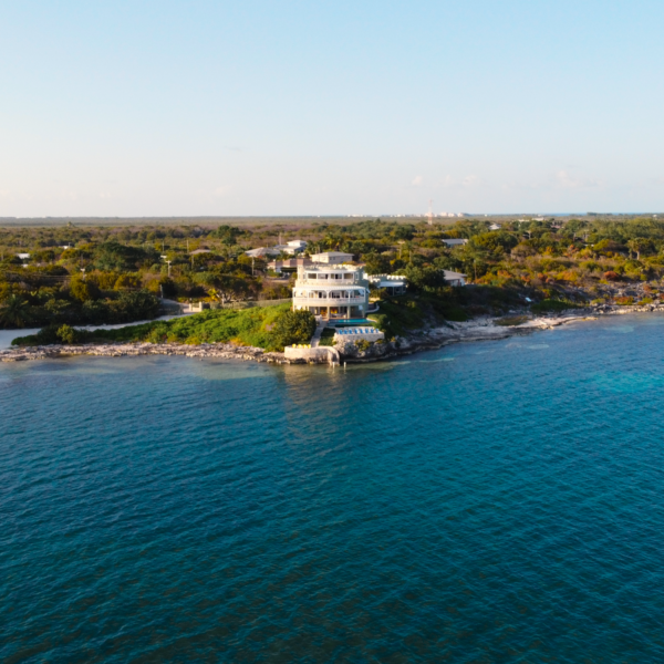 A scenic aerial view of a luxury beachfront estate in Grand Cayman with lush greenery and azure waters.