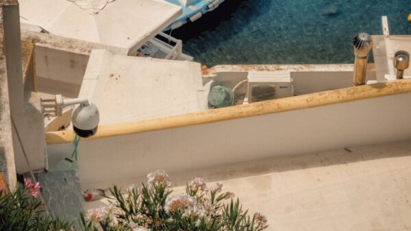 A blue boat moored in clear water beside a white terrace with flowers.