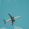 A commercial airplane soars through a bright blue sky, showcasing aviation travel.