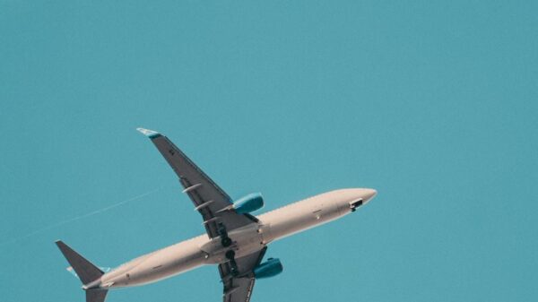 A commercial airplane soars through a bright blue sky, showcasing aviation travel.