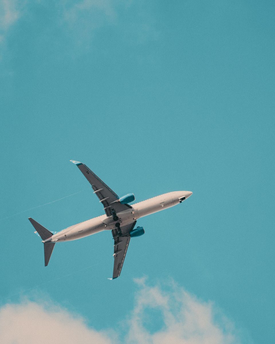 A commercial airplane soars through a bright blue sky, showcasing aviation travel.