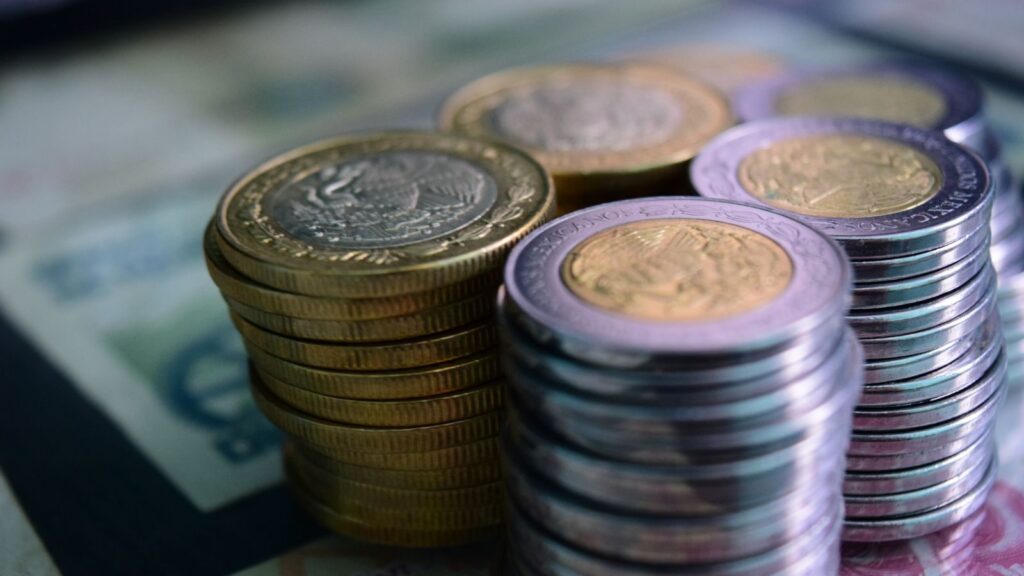 Close-up of stacked gold and silver coins on various currency notes, symbolizing wealth and savings.