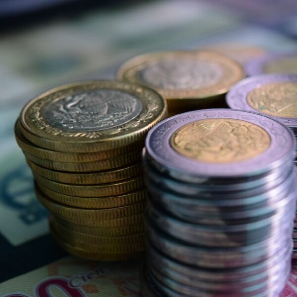 Close-up of stacked gold and silver coins on various currency notes, symbolizing wealth and savings.