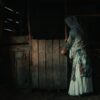 a woman in a white dress standing in a barn