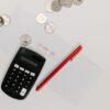 Calculator, pen, and coins on an envelope labeled 'Income Tax' for tax preparation.
