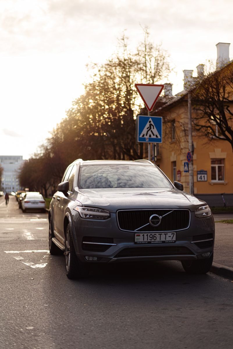 A Volvo XC90 parked on a city street with a beautiful sunlight backdrop.