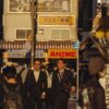 Crowded street in Tokyo with business people and anime signs in warm daylight.