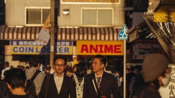 Crowded street in Tokyo with business people and anime signs in warm daylight.