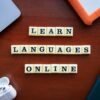 Flat lay of language learning tools with devices and text blocks on desk.