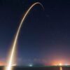 Spectacular long exposure of a rocket launch under a clear, starry night sky showcasing the trail.