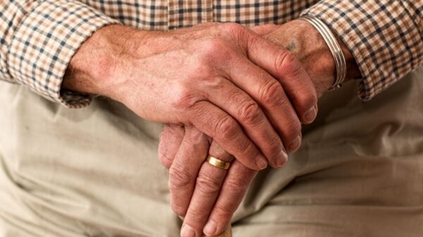 A detailed image of elderly hands clasping a wooden cane, symbolizing aging and support.