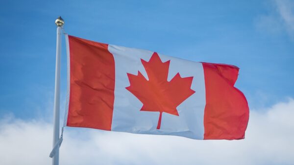 A vibrant Canadian flag waving in the breeze against a bright blue sky, symbolizing national pride.
