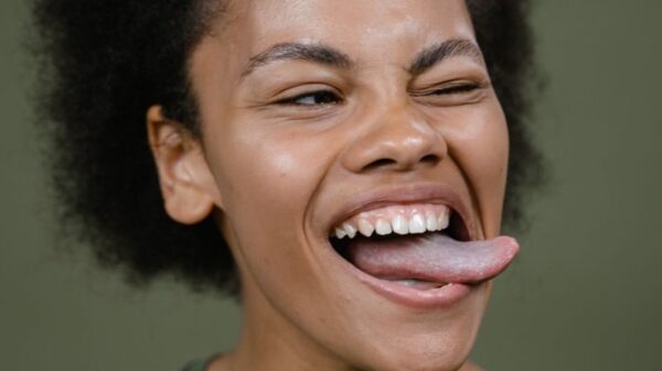 Close-up of a smiling woman with afro hair making a playful expression against a green background in a studio.