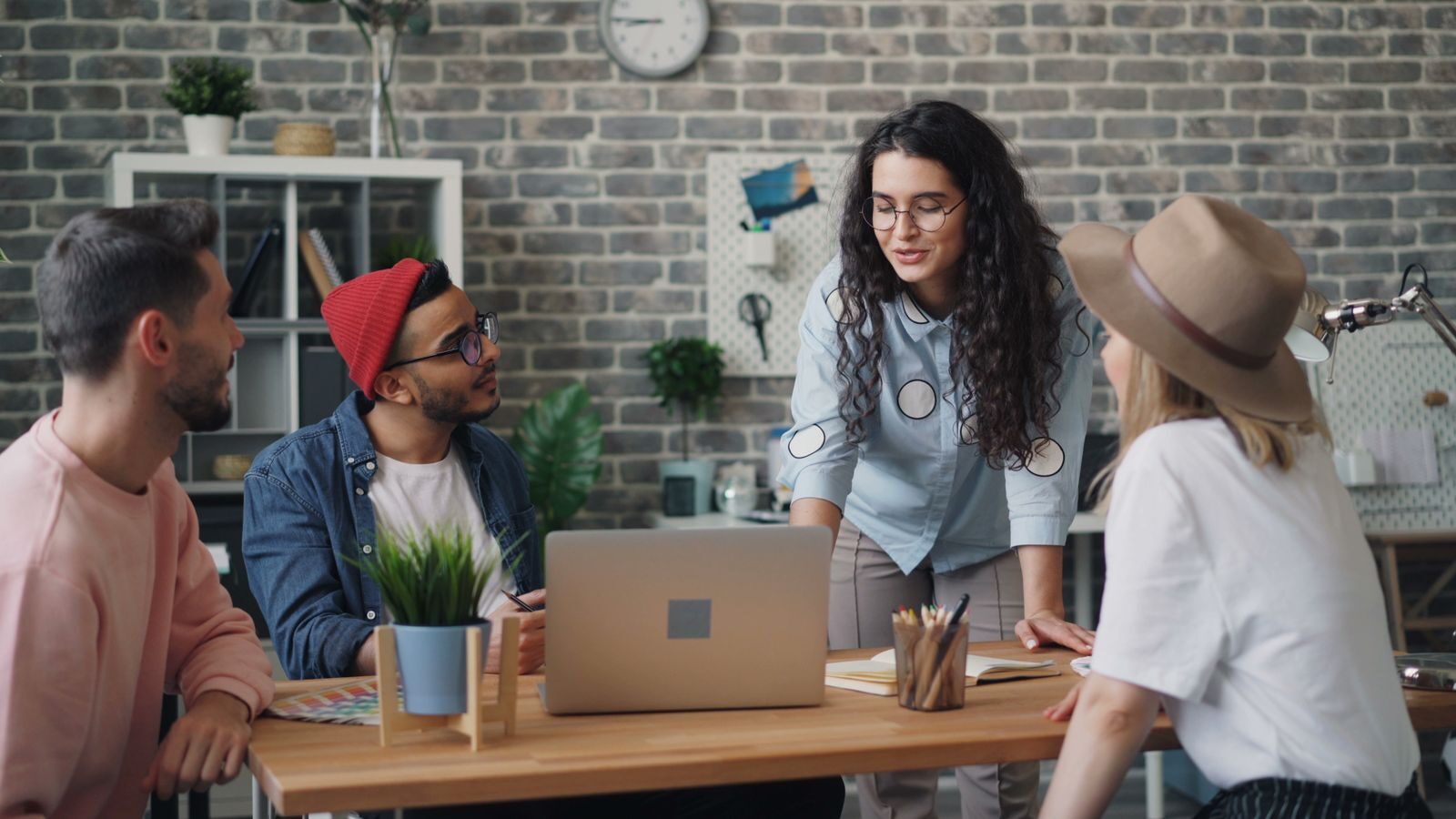 A diverse group of creative professionals discussing ideas in a modern office with a laptop.