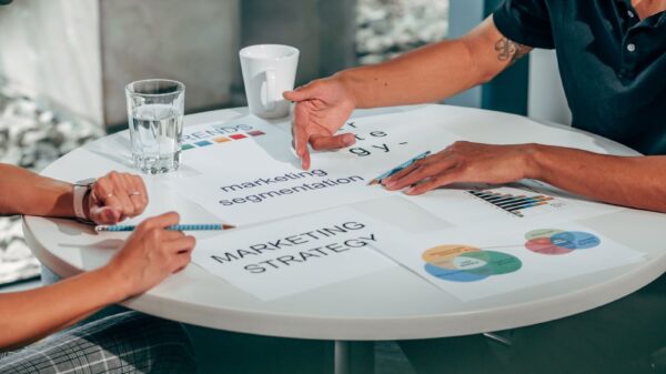 Two adults in an office discussing marketing strategy around a round table.