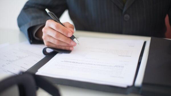 Close-up of a hand signing documents with a pen, symbolizing an important business contract.